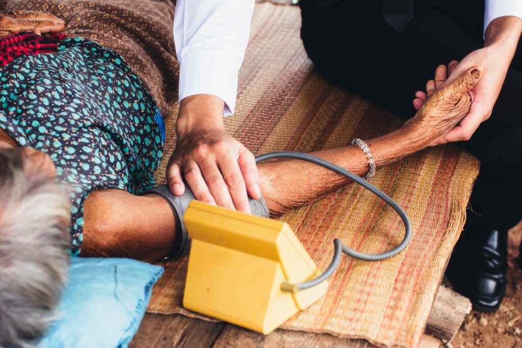 Male Doctor listening heart beat and breathing of Elderly Woman with Stethoscope with First Aid Medical Box.Community Health and Development Hospital In Remote Areas Development Fund Concept.